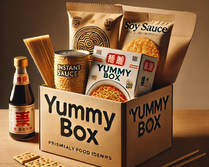 Yummy Box mit asiatischen Lebensmitteln, darunter Instantnudeln, eine Sojasauce-Flasche und Reissnacks, minimalistisch auf einem Holztisch arrangiert.